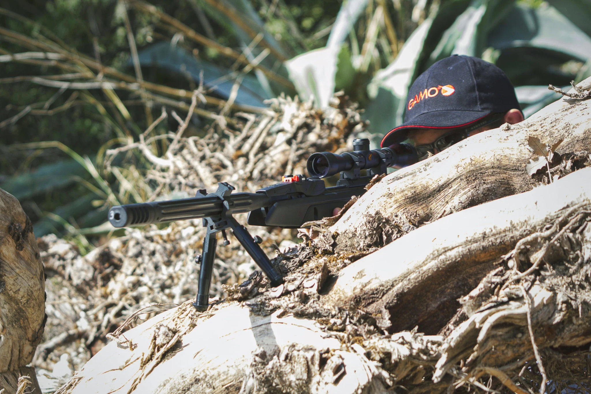 Gamo Official Optics Action Adult shooter aiming a scoped Gamo air rifle in an official Gamo image
